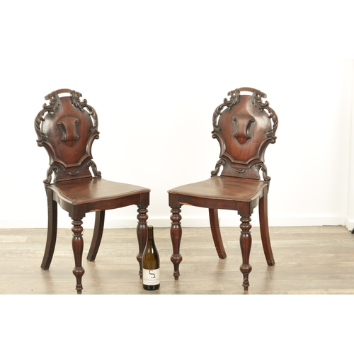 1368 - A PAIR OF 19TH CENTURY MAHOGANY HALL CHAIRS with leaf-carved shaped backs and raised on ring turned ... 