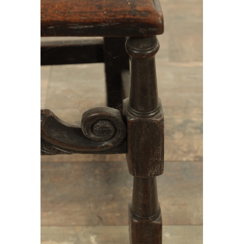 1383 - A CHARLES II OAK HALL CHAIR with a raised slatted back and panelled seat above turned legs and carve... 