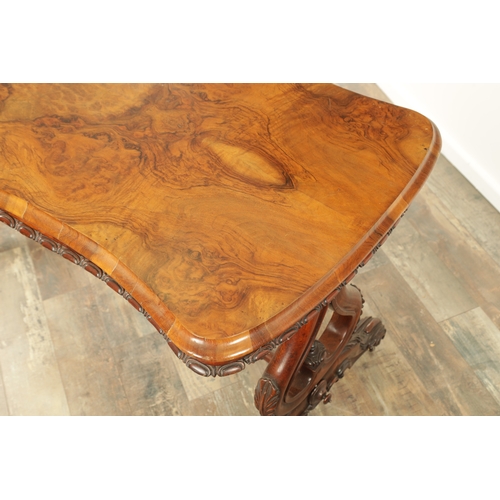 1416 - A VICTORIAN BURR WALNUT SERPENTINE SHAPED LIBRARY TABLE with moulded edge top above leaf carved end ... 