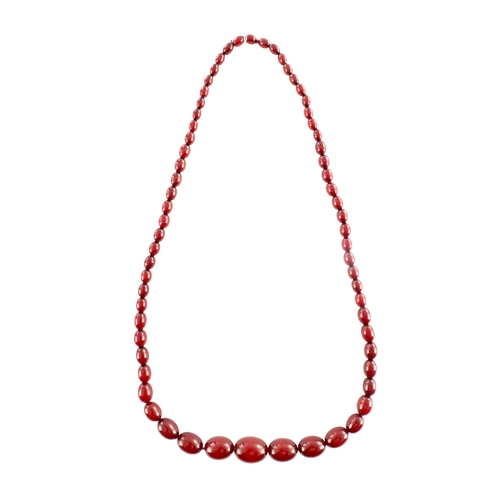 102 - A GRADUATED CHERRY AMBER OVAL BEAD NECKLACE, with red string, largest bead measures 28mm long. Total... 