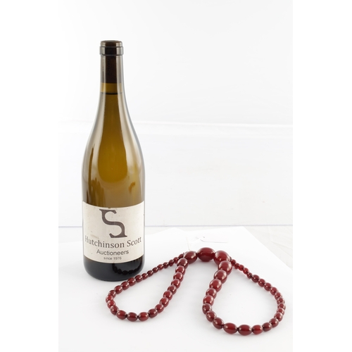 102 - A GRADUATED CHERRY AMBER OVAL BEAD NECKLACE, with red string, largest bead measures 28mm long. Total... 