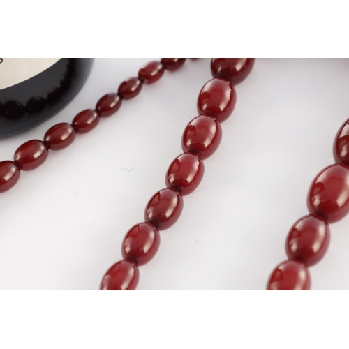 102 - A GRADUATED CHERRY AMBER OVAL BEAD NECKLACE, with red string, largest bead measures 28mm long. Total... 