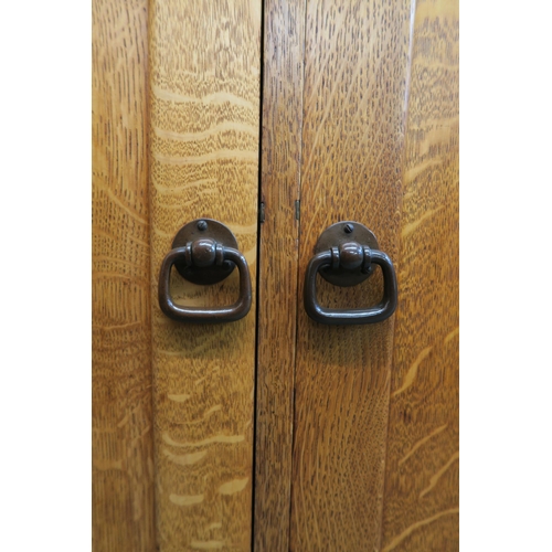 88 - An early 20th century Taylor & Whitfield ltd oak two door cabinet with bronzed door furniture 125cm ... 