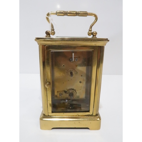 221 - A brass carriage clock with white enamel dial and roman numeral chapter ring