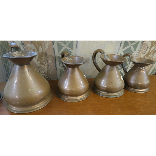 116 - A graduated set of eight copper measures ranging from a gil to a gallon and a large copper funnel (9... 