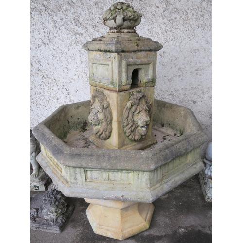 141 - An octagonal stone garden water fountain with lion reliefs, 120cm high x 90cm wide x 90cm deep