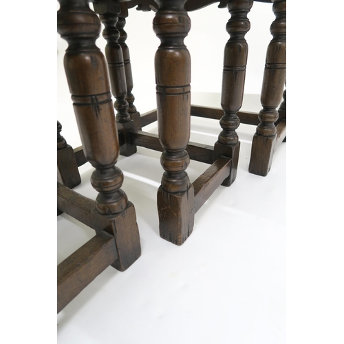 20 - A 20th century stained oak nest of three tables on turned stretched supports, 50cm high x 51cm wide ... 