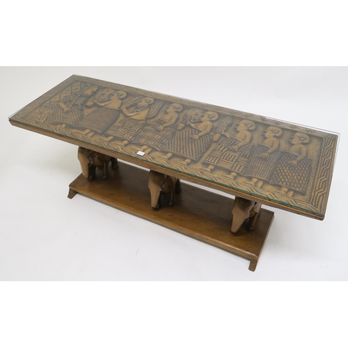 77 - A 20th century carved African hardwood coffee table with carved elephant supports, 43cm high x 122cm... 