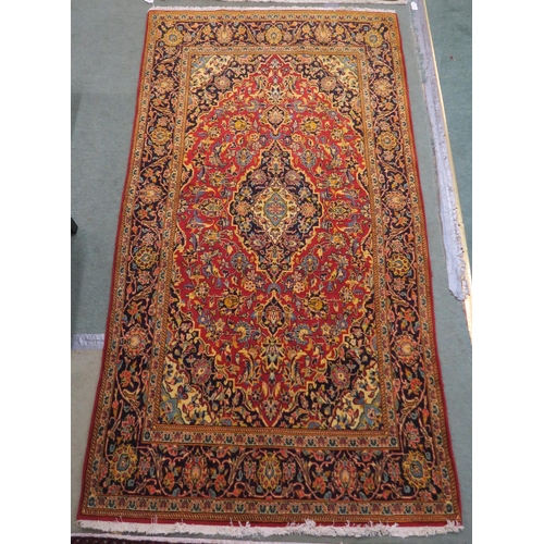 84 - A red ground fine Keshan rug with central medallion, matching spandrels and dark blue border, 230cm ... 