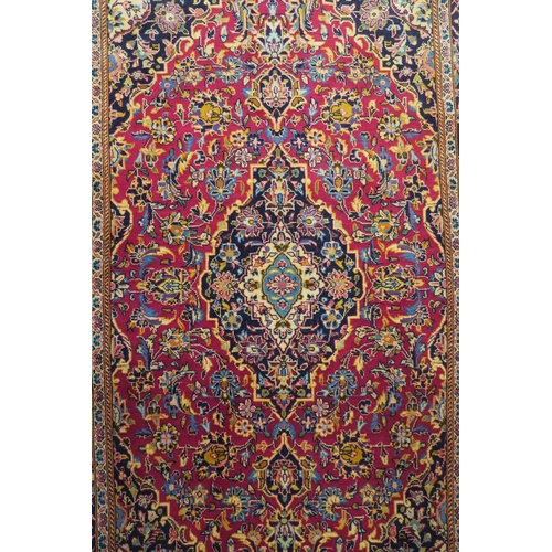 84 - A red ground fine Keshan rug with central medallion, matching spandrels and dark blue border, 230cm ... 