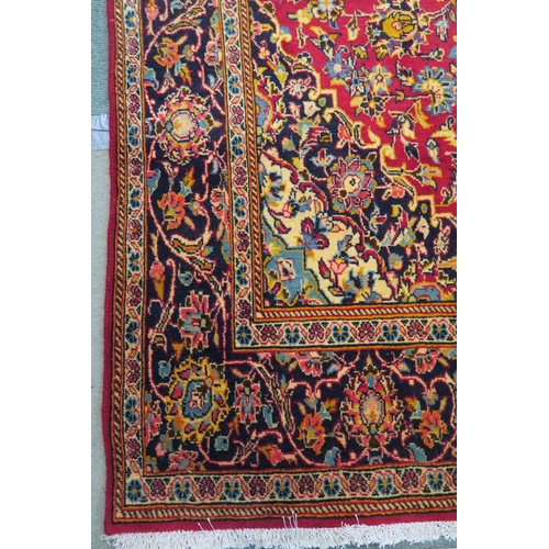 84 - A red ground fine Keshan rug with central medallion, matching spandrels and dark blue border, 230cm ... 