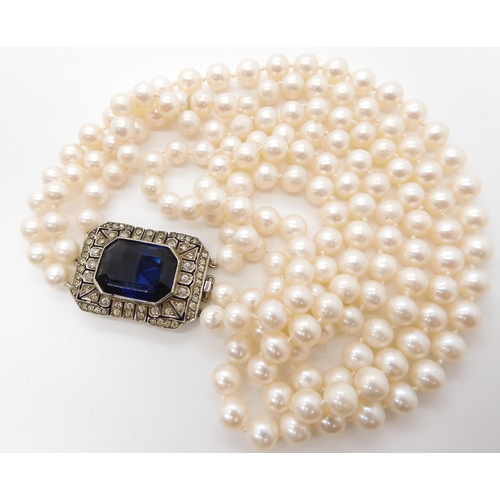 541 - A three strand pearl necklace with a decorative continental silver diamante and blue gem set clasp