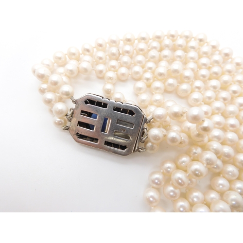 541 - A three strand pearl necklace with a decorative continental silver diamante and blue gem set clasp