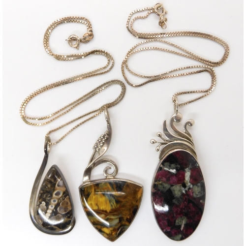 647 - Three American designer pendants by Tom Burns, of Vermont, set with blue and gold tiger's eye, fossi... 