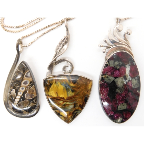 647 - Three American designer pendants by Tom Burns, of Vermont, set with blue and gold tiger's eye, fossi... 