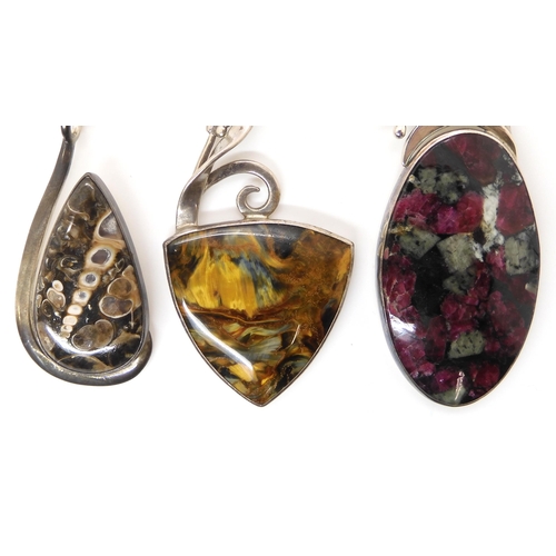 647 - Three American designer pendants by Tom Burns, of Vermont, set with blue and gold tiger's eye, fossi... 