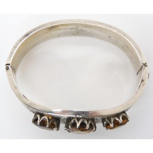 664 - A white metal bangle set with citrines, with hand engraved decoration