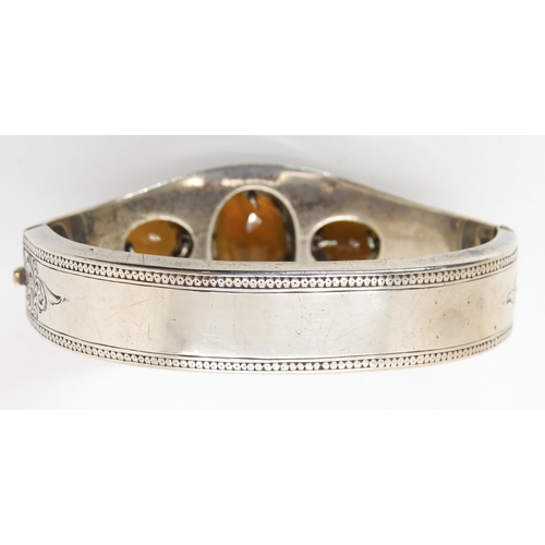 664 - A white metal bangle set with citrines, with hand engraved decoration