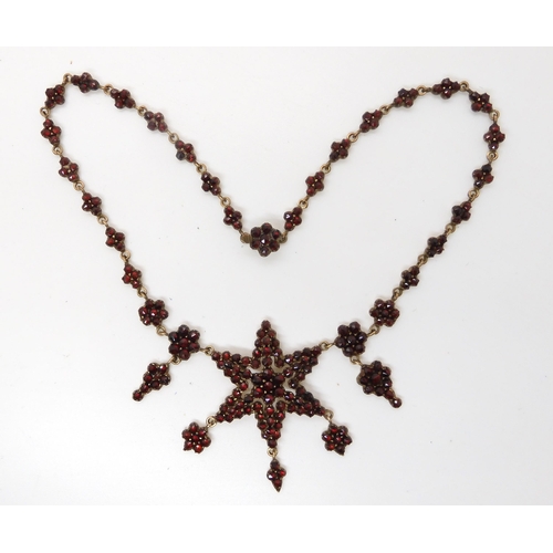 666 - A gilded white metal red gem set star necklace