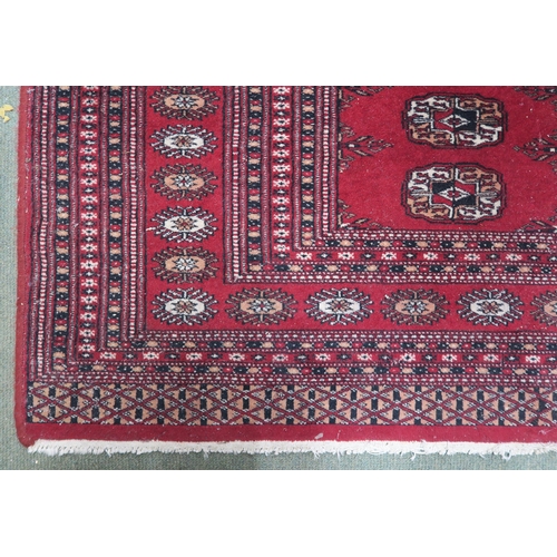 27 - A red ground Bokhara style rug with all over lozenge design, 188cm long x 127cm wide