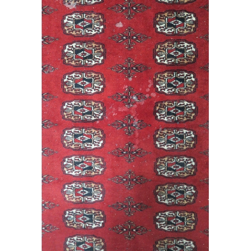 27 - A red ground Bokhara style rug with all over lozenge design, 188cm long x 127cm wide