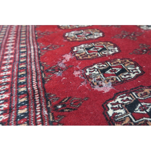 27 - A red ground Bokhara style rug with all over lozenge design, 188cm long x 127cm wide