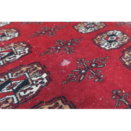 27 - A red ground Bokhara style rug with all over lozenge design, 188cm long x 127cm wide