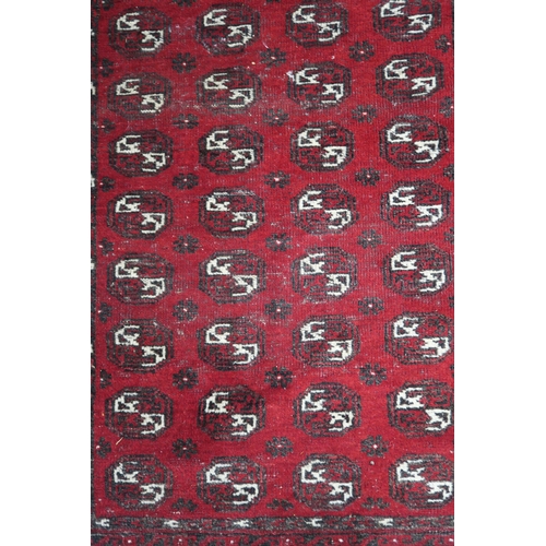 63 - A red ground Bokhara rug with all over lozenge design, 179cm long x 133cm wide...