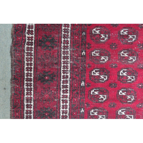 63 - A red ground Bokhara rug with all over lozenge design, 179cm long x 133cm wide