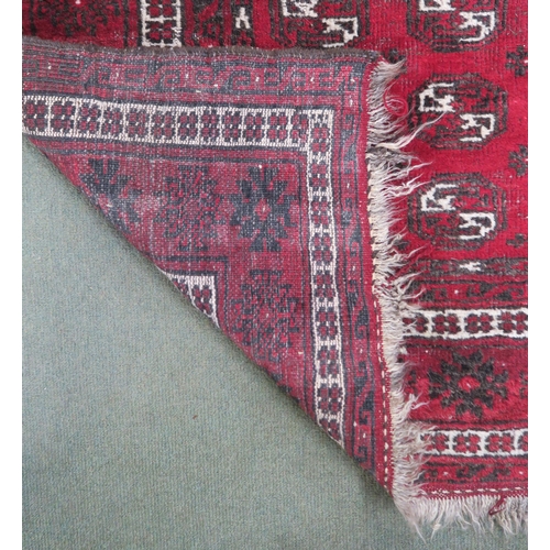 63 - A red ground Bokhara rug with all over lozenge design, 179cm long x 133cm wide