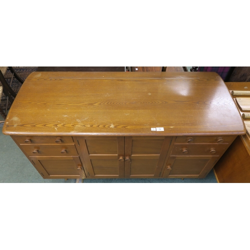 73 - A mid 20th century elm and beech Ercol sideboard with two central cabinet doors flanked by two drawe... 