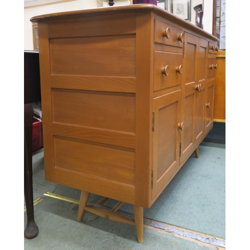 73 - A mid 20th century elm and beech Ercol sideboard with two central cabinet doors flanked by two drawe... 