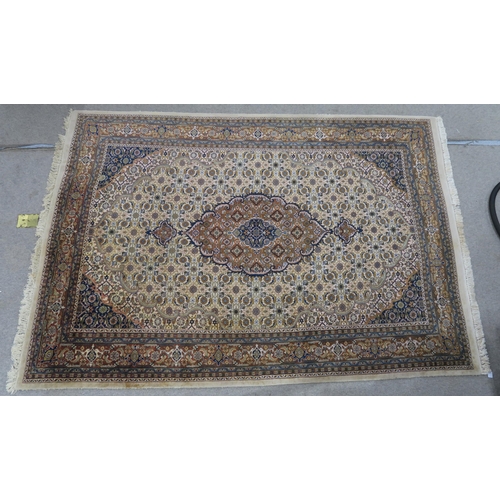 124 - A CREAM GROUND TABRIZ RUG with a light terracotta medallion, matching borders and dark blue spandrel... 