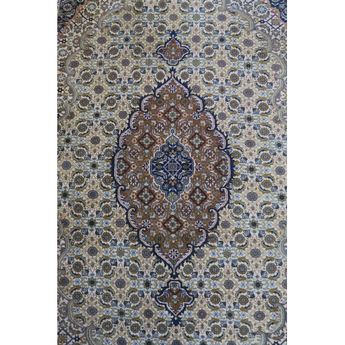 124 - A CREAM GROUND TABRIZ RUG with a light terracotta medallion, matching borders and dark blue spandrel... 