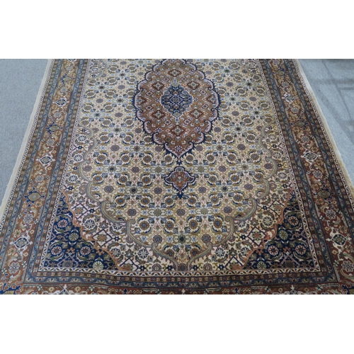 124 - A CREAM GROUND TABRIZ RUG with a light terracotta medallion, matching borders and dark blue spandrel... 