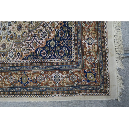 124 - A CREAM GROUND TABRIZ RUG with a light terracotta medallion, matching borders and dark blue spandrel... 