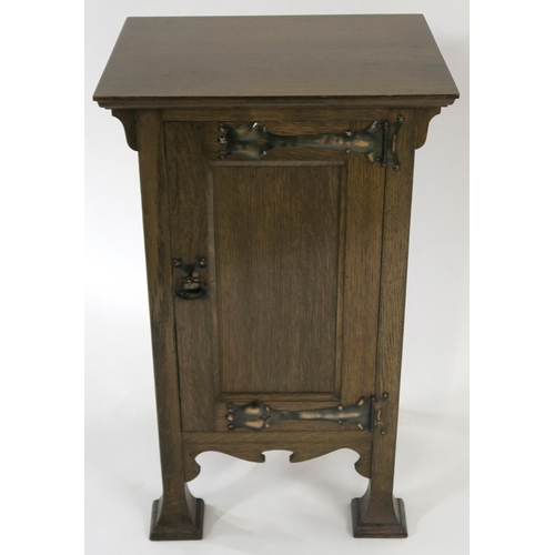 22 - AN OAK ARTS AND CRAFTS BEDSIDE CABINET BY HENRY BARKER LTD NOTTINGHAM with panel door mounted with s... 