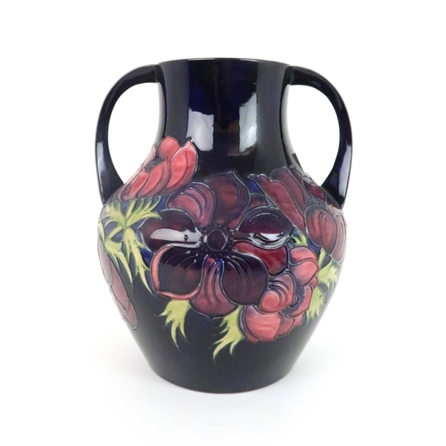 353 - A LARGE MOORCROFT ANEMONE PATTERN TWO HANDLED VASE the dark blue ground with pink/purple flowers, da... 