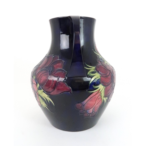 353 - A LARGE MOORCROFT ANEMONE PATTERN TWO HANDLED VASE the dark blue ground with pink/purple flowers, da... 