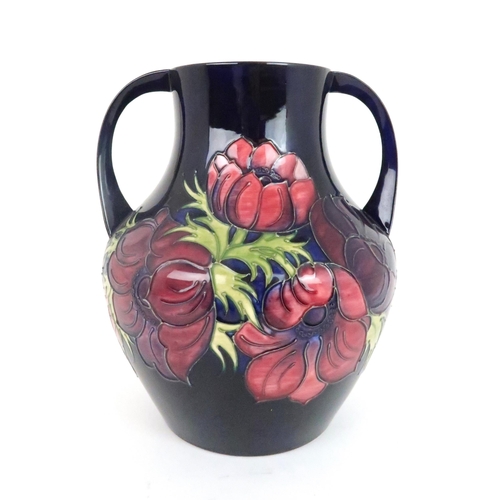 353 - A LARGE MOORCROFT ANEMONE PATTERN TWO HANDLED VASE the dark blue ground with pink/purple flowers, da... 