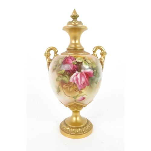 364 - A ROYAL WORCESTER URN AND COVER decorated with roses and foliage, with gilded handles, neck and base... 