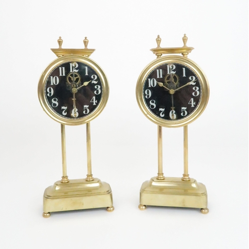 379 - A NEAR PAIR OF BRASS KEY LESS GRAVITY CLOCKSthe glass dial with white painted arabic numerals, both ... 