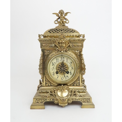 398 - A FRENCH BRASS MANTLE CLOCKwith cherub finial and central mask above the dial, the dial with arabic ... 