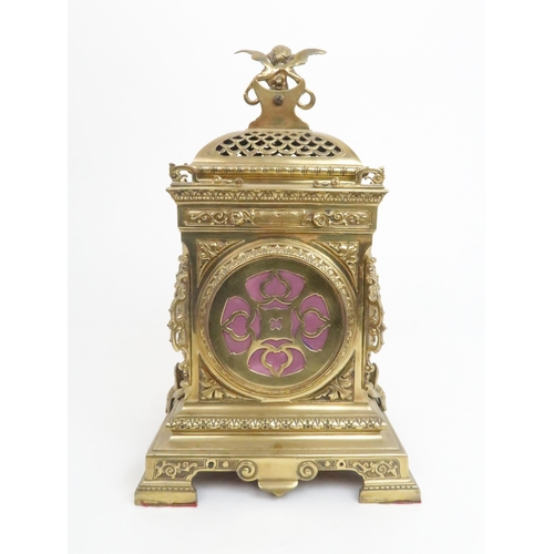 398 - A FRENCH BRASS MANTLE CLOCKwith cherub finial and central mask above the dial, the dial with arabic ... 