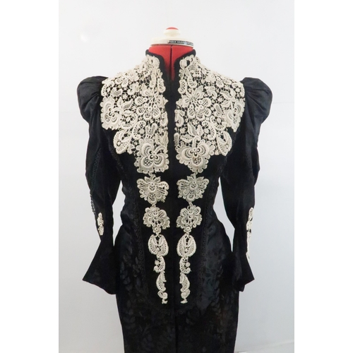 571 - A VICTORIAN MOURNING DRESS IN BLACK FLORALpatterned crepe with applied white lace to black velvet co... 