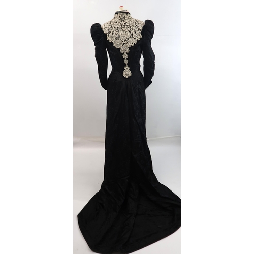 571 - A VICTORIAN MOURNING DRESS IN BLACK FLORALpatterned crepe with applied white lace to black velvet co... 