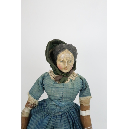 574 - AN EARLY PAPIER MACHE SHOULDER HEAD DOLLwith painted features, with dress and bonnet, 69cm long and ... 