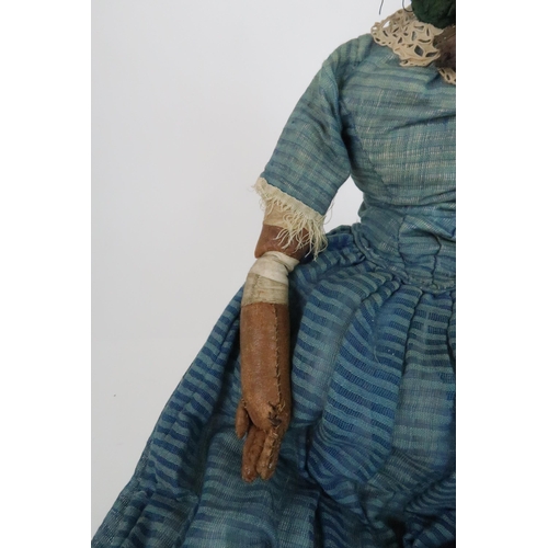 574 - AN EARLY PAPIER MACHE SHOULDER HEAD DOLLwith painted features, with dress and bonnet, 69cm long and ... 