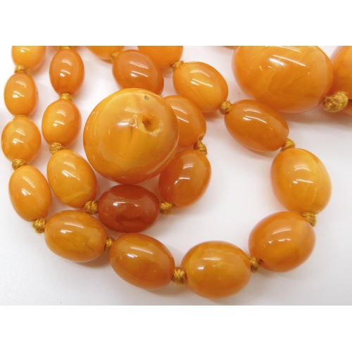 707 - A STRING OF BUTTERSCOTCH COLOUR AMBER BEADS strung length 97cm, weight 74.6gms (with one spare loose... 