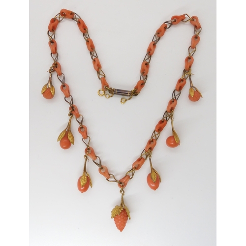 824 - A CARVED CORAL FRUIT NECKLACEthe fruit mounted with engraved and chased yellow metal leaves, with co... 